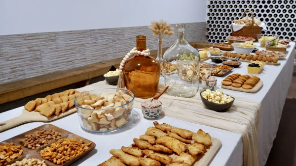 Mesa de catering para festa de aniversário com variedade de salgados, snacks, pão, folhados e decoração elegante preparada pela Aperidrinks.